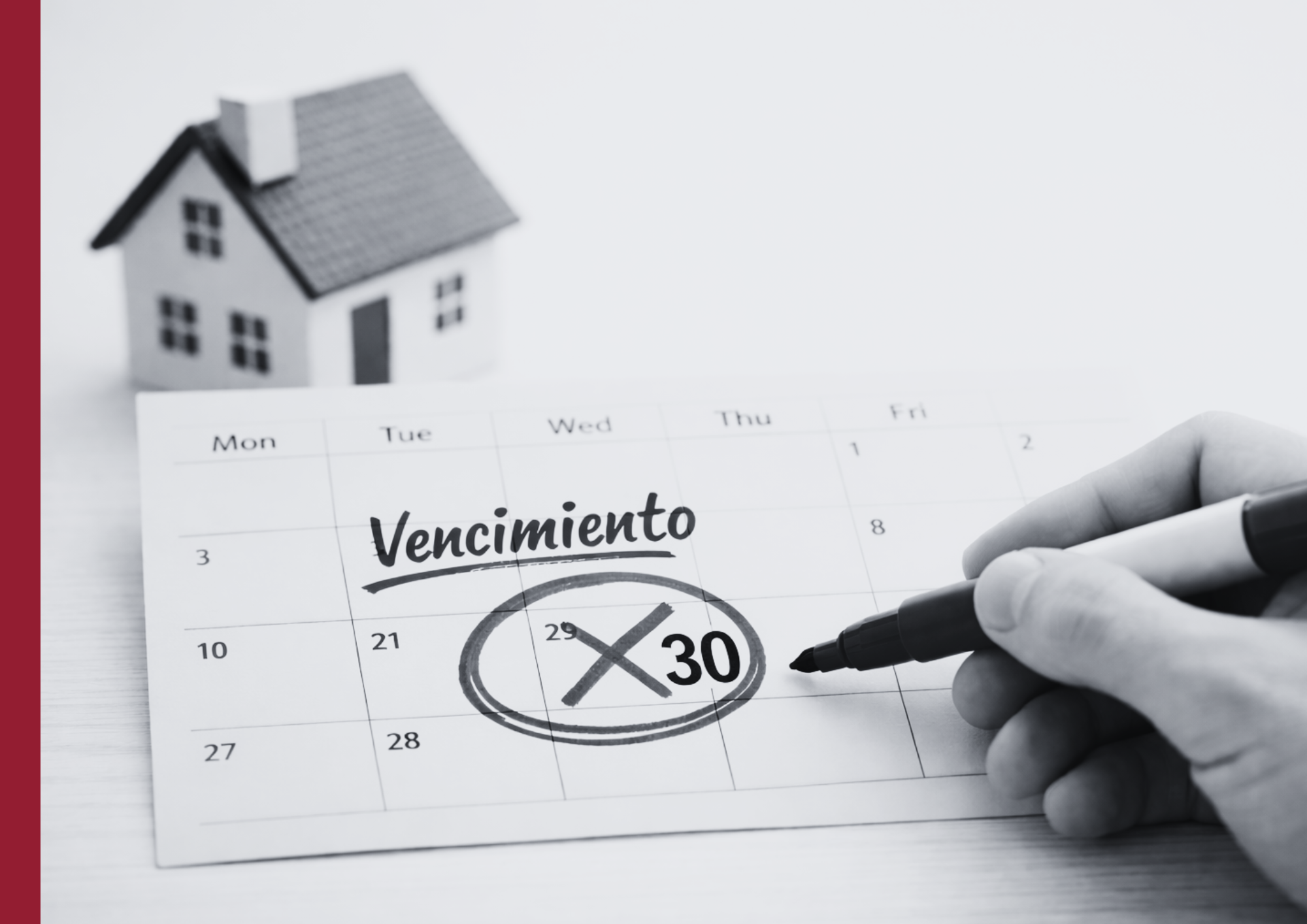 Calendario con la fecha de vencimiento del seguro de hogar marcada en rojo y una maqueta de casa al fondo