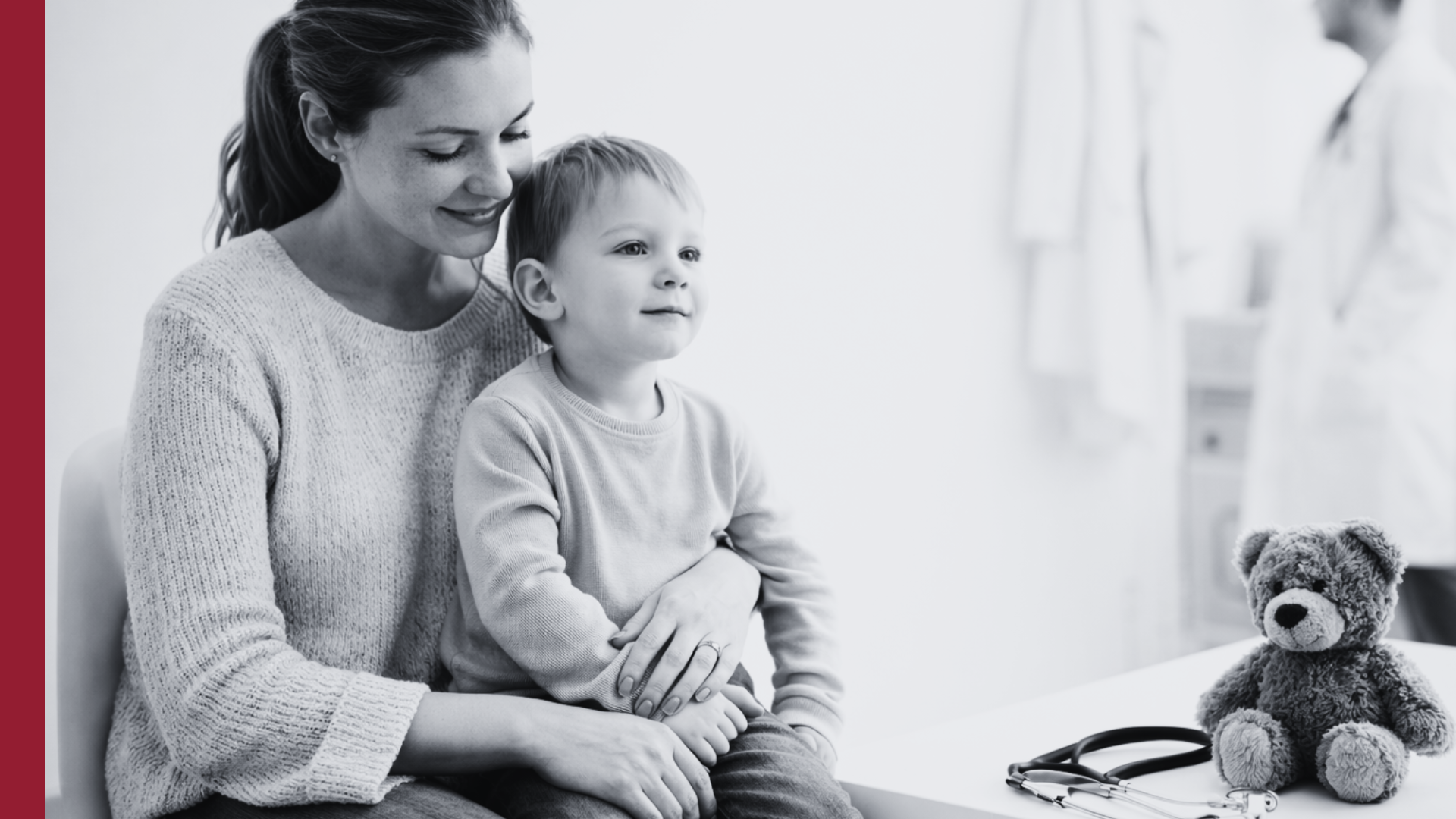 Madre con su hijo en una sala de espera pediátrica, con un peluche y un estetoscopio sobre la mesa y un médico al fondo desenfocado
